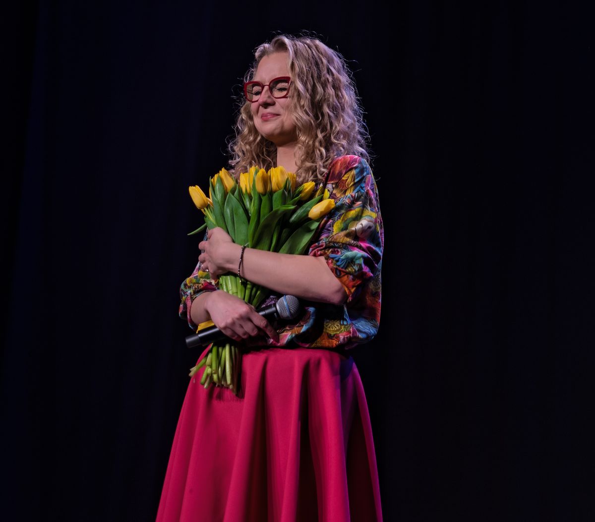 Aleksandra Radomska na scenie z bukietem żółtych tulipanów