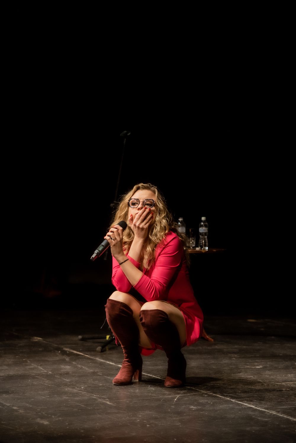 Kadr z występu - Aleksandra kuca na scenie z mikrofonem