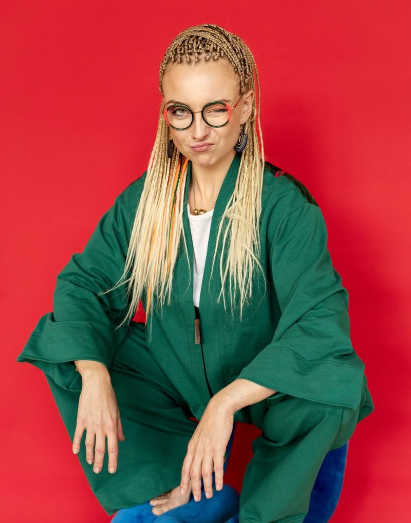 Aleksandra Radomska w zielonym komplecie na czerwonym tle